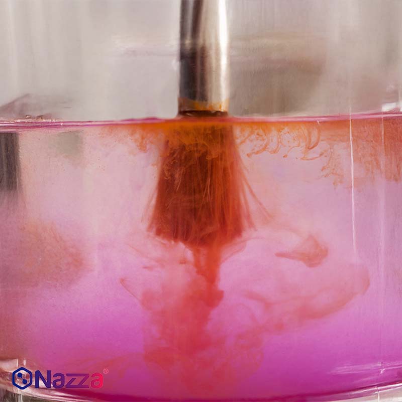 Primeiro plano de uma trincha mergulhada num líquido transparente, onde se observa como a cor se dissolve e se dispersa, ilustrando visualmente a ação de um solvente sobre restos de tinta. Uma imagem clara e didática para representar o processo de limpeza e diluição em trabalhos de pintura.